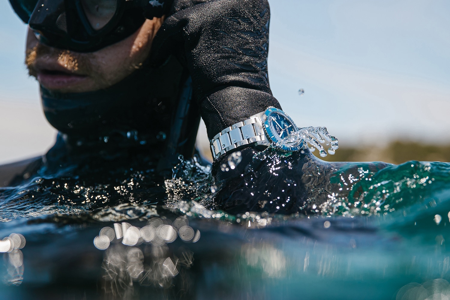 Close up of a man's wrist with a Glashutte watch above sea water