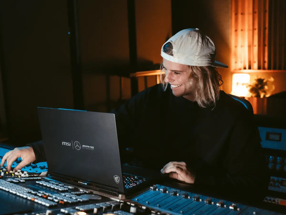 Man with an MSI laptop adjusting the sound equipment in a recording studio