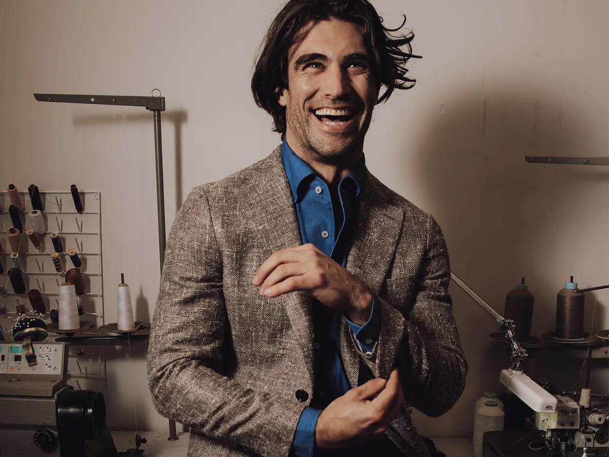 Man in a brown suit and blue button-down shirt smiling